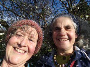 2 women smilings beside a hedge