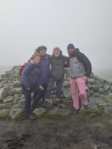 4 walkers in the mist at the top of a hill