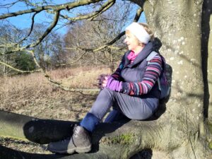 a WOMAN SITTING ON THE BRANCH OF A TREE IN THE SUN