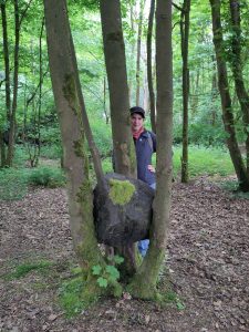 Jo standing behind some trees in which a stone is suspended