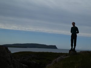 Man standing on a rock with Canna behind