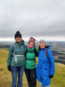 3 women in walking gear on top of a hill